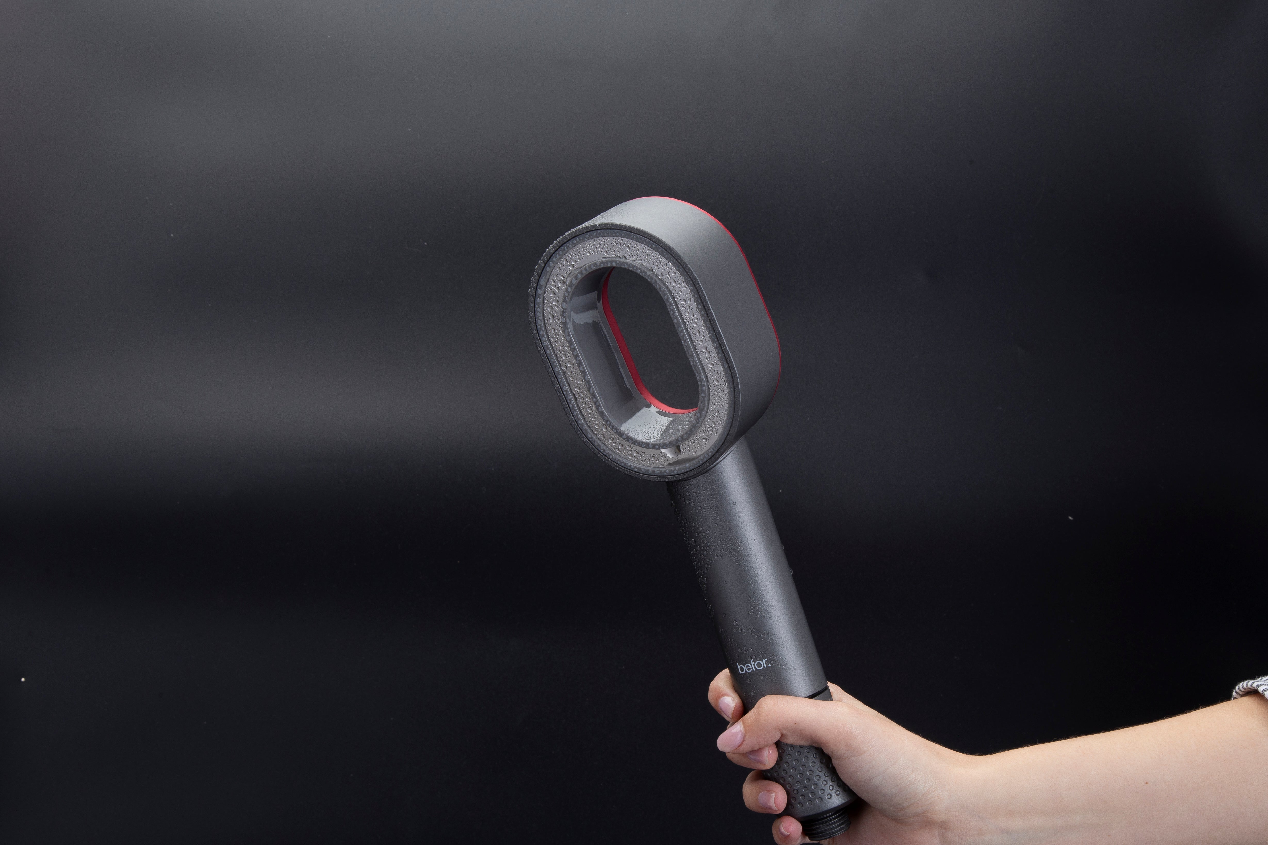 Hand holding a gray handheld filtered showerhead