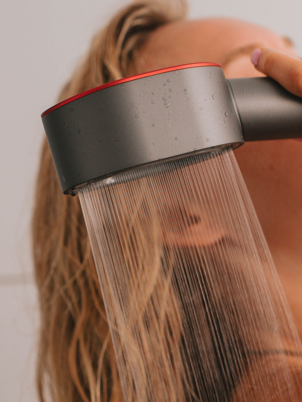 Person using a showerhead with water flowing, blurred background
